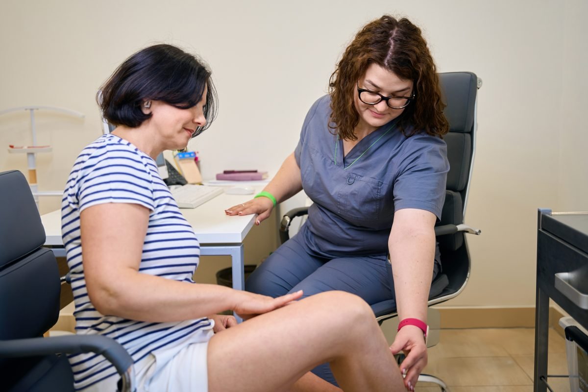 Vein specialist examining a patient’s leg during consultation. 
